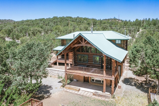 76 Los Altos De Cicuye, Pecos, NM 87552 - rear view of house with a view of trees, log siding, a patio, and metal roof