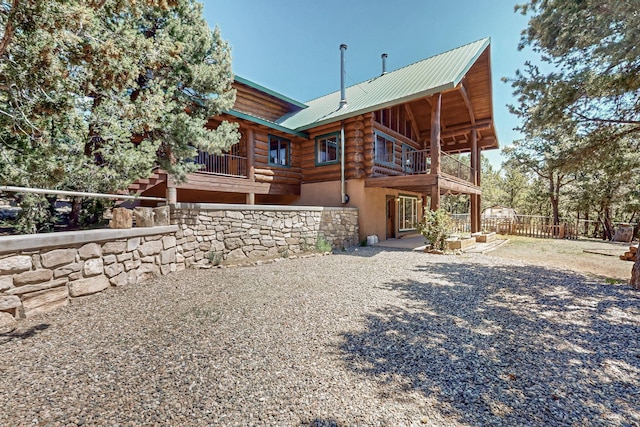 76 Los Altos De Cicuye, Pecos, NM 87552 - rear view of house featuring log siding, a balcony, metal roof, and a patio