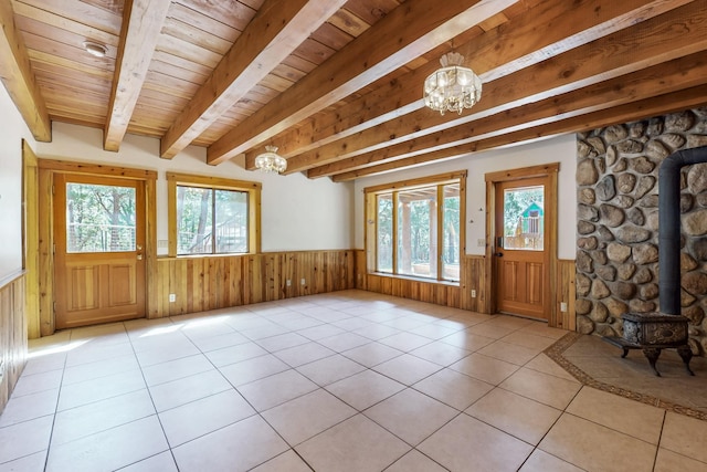 76 Los Altos De Cicuye, Pecos, NM 87552 - foyer entrance with a chandelier, a wood stove, a wainscoted wall, healthy amount of natural light, and wood ceiling with exposed beams