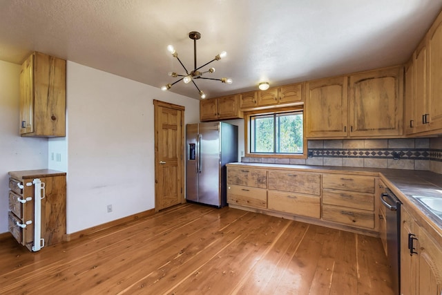 76 Los Altos De Cicuye, Pecos, NM 87552 - kitchen with stainless steel appliances, a chandelier, light wood-type flooring, tasteful backsplash, and tile counters