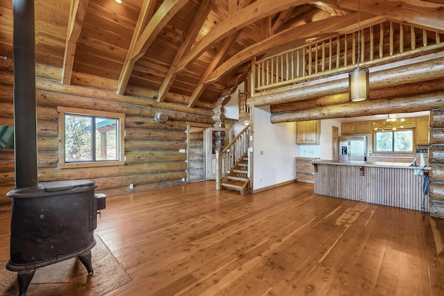 76 Los Altos De Cicuye, Pecos, NM 87552 - unfurnished living room featuring a wood stove, high vaulted ceiling, wood-type flooring, stairway, and wooden ceiling with exposed beams