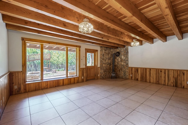 76 Los Altos De Cicuye, Pecos, NM 87552 - empty room featuring a wood stove, a wainscoted wall, wood ceiling with exposed beams, a chandelier, and wooden walls
