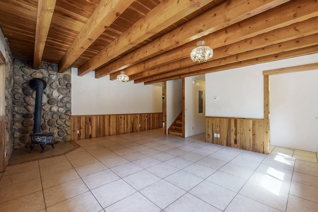 76 Los Altos De Cicuye, Pecos, NM 87552 - unfurnished room with wainscoting, wood ceiling with exposed beams, a wood stove, wooden walls, and stairs