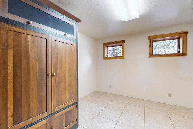 76 Los Altos De Cicuye, Pecos, NM 87552 - unfurnished bedroom with a textured ceiling and light tile patterned floors