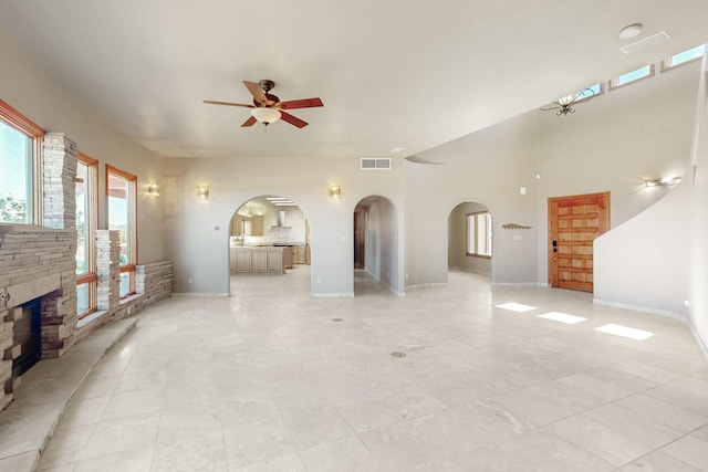 5 La Aguapa, Sandia Park, NM 87047 - unfurnished living room with a ceiling fan, arched walkways, a stone fireplace, and baseboards