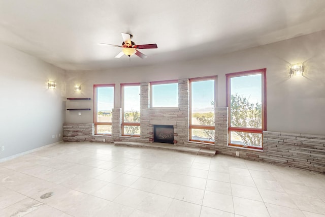 5 La Aguapa, Sandia Park, NM 87047 - unfurnished living room with ceiling fan, light tile patterned floors, and a stone fireplace