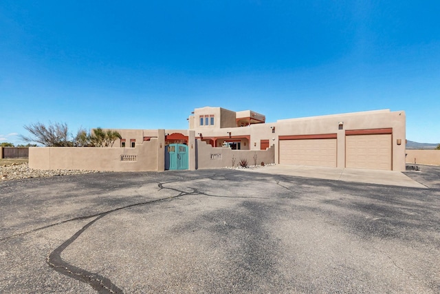 5 La Aguapa, Sandia Park, NM 87047 - adobe home featuring stucco siding, driveway, a garage, and a gate