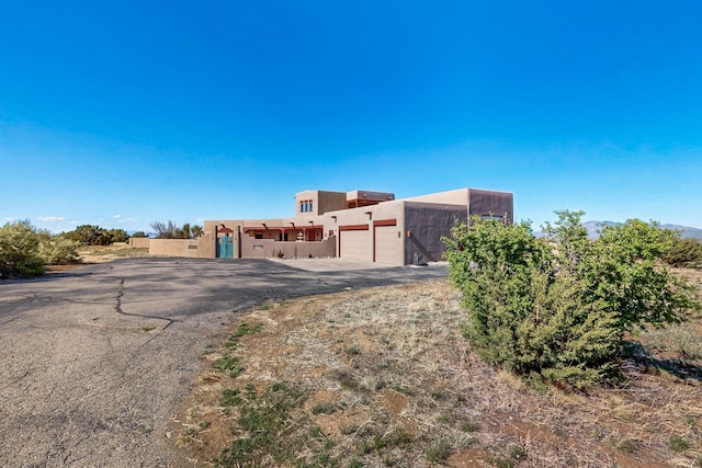 5 La Aguapa, Sandia Park, NM 87047 - adobe home featuring an attached garage, stucco siding, and driveway