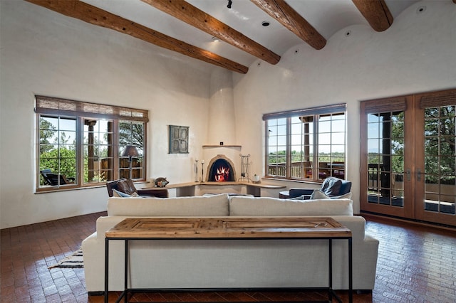 1050 Sierra Del Norte, Santa Fe, NM 87501 - living area with brick floors, beamed ceiling, french doors, a warm lit fireplace, and a high ceiling