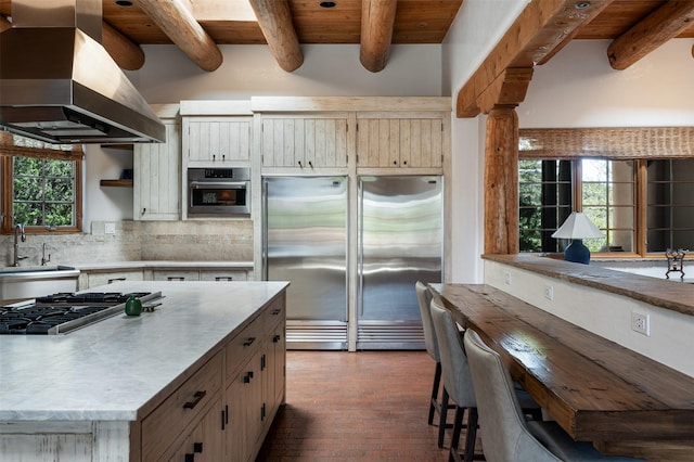 1050 Sierra Del Norte, Santa Fe, NM 87501 - kitchen with island exhaust hood, appliances with stainless steel finishes, light countertops, decorative backsplash, and wooden ceiling with exposed beams