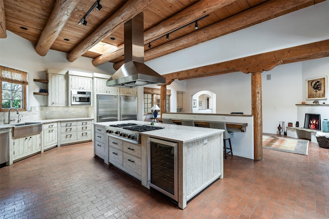 1050 Sierra Del Norte, Santa Fe, NM 87501 - kitchen featuring wooden ceiling with exposed beams, beverage cooler, stainless steel appliances, a sink, and brick flooring