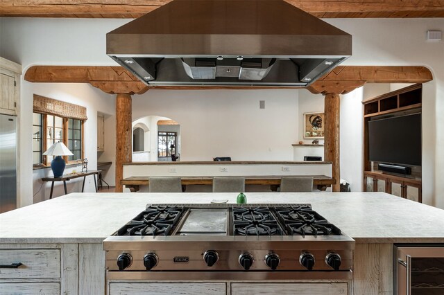 1050 Sierra Del Norte, Santa Fe, NM 87501 - kitchen with beverage cooler, stainless steel gas stovetop, light countertops, wall chimney range hood, and wood ceiling