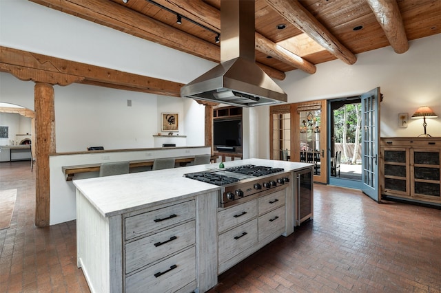 1050 Sierra Del Norte, Santa Fe, NM 87501 - kitchen with wooden ceiling with exposed beams, stainless steel gas cooktop, brick flooring, wine cooler, and island range hood