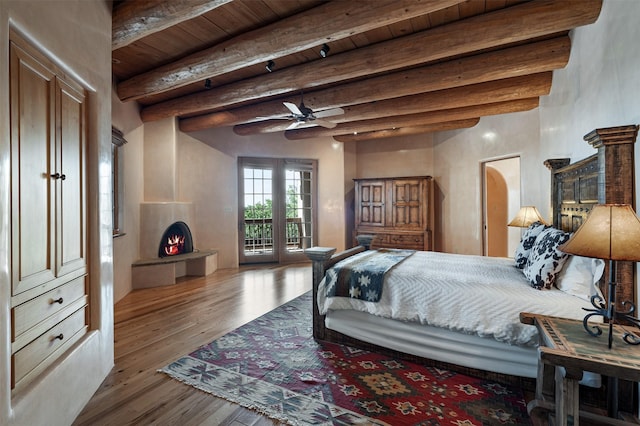 1050 Sierra Del Norte, Santa Fe, NM 87501 - bedroom with a lit fireplace, access to exterior, hardwood / wood-style floors, and wood ceiling with exposed beams