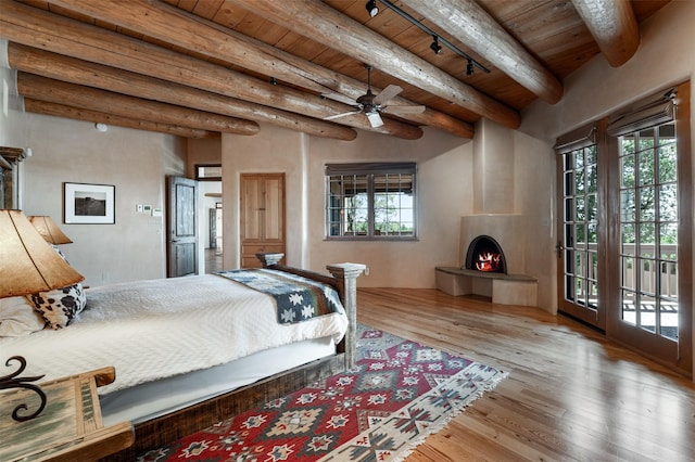 1050 Sierra Del Norte, Santa Fe, NM 87501 - bedroom with wood ceiling with exposed beams, access to outside, wood finished floors, a large fireplace, and rail lighting