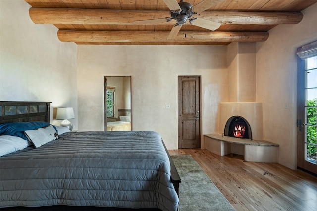 1050 Sierra Del Norte, Santa Fe, NM 87501 - bedroom with wooden ceiling with exposed beams, light wood-type flooring, and a warm lit fireplace