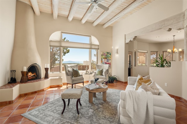 28 Camino Caballos, Lamy, NM 87540 - living area with wood ceiling with exposed beams, a ceiling fan, a large fireplace, tile patterned flooring, and a chandelier