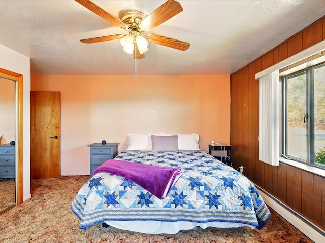 707 Middle San Pedro Rd, Espanola, NM 87532 - carpeted bedroom featuring a baseboard heating unit, wood walls, and ceiling fan