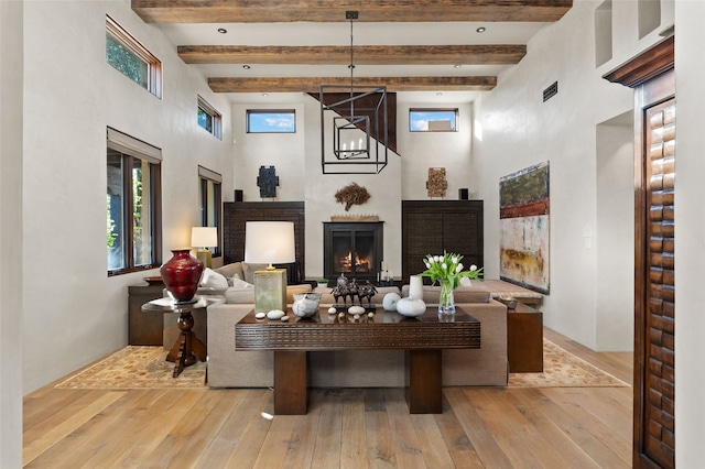 20 Rising Moon, Santa Fe, NM 87506 - living area with a high ceiling, hardwood / wood-style flooring, a warm lit fireplace, beamed ceiling, and plenty of natural light