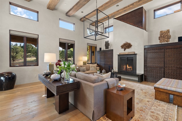 20 Rising Moon, Santa Fe, NM 87506 - living room with a high ceiling, light wood-style flooring, a warm lit fireplace, and beam ceiling