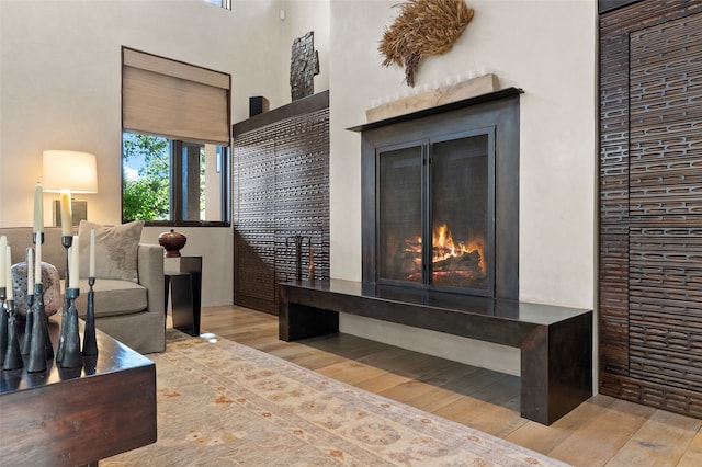 20 Rising Moon, Santa Fe, NM 87506 - living room featuring a warm lit fireplace, wood finished floors, and a high ceiling