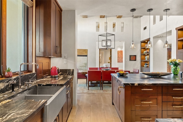 20 Rising Moon, Santa Fe, NM 87506 - kitchen with a sink, light wood-style floors, decorative light fixtures, a high ceiling, and dark stone countertops