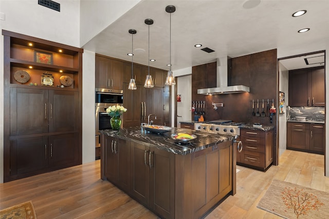 20 Rising Moon, Santa Fe, NM 87506 - kitchen with wall chimney range hood, light wood-style floors, decorative backsplash, dark brown cabinetry, and recessed lighting