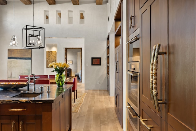 20 Rising Moon, Santa Fe, NM 87506 - kitchen featuring a sink, a warming drawer, light wood-style flooring, a towering ceiling, and pendant lighting