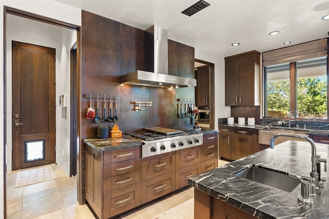 20 Rising Moon, Santa Fe, NM 87506 - kitchen featuring wall chimney range hood, stainless steel gas cooktop, recessed lighting, tasteful backsplash, and dark stone counters