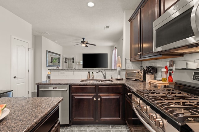 5910 Monte Rosa St, Santa Fe, NM 87507 - kitchen with appliances with stainless steel finishes, a sink, decorative backsplash, ceiling fan, and dark stone countertops