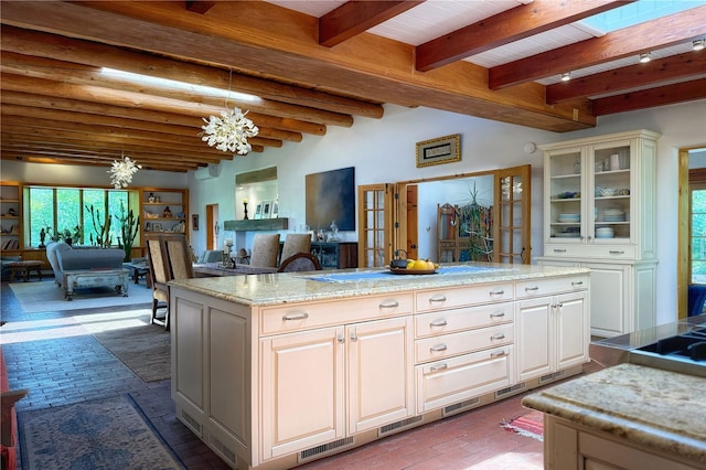 559 Camino Del Monte Sol, Santa Fe, NM 87505 - kitchen featuring a chandelier, brick flooring, glass insert cabinets, open floor plan, and light stone countertops