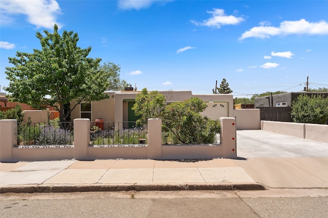 1208 Declovina St, Santa Fe, NM 87505 - adobe home featuring concrete driveway, a fenced front yard, stucco siding, and an attached garage