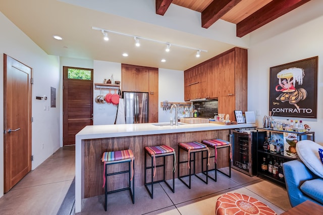 543 Juanita Unit B, Santa Fe, NM 87501 - kitchen featuring beverage cooler, freestanding refrigerator, brown cabinetry, a peninsula, and a breakfast bar