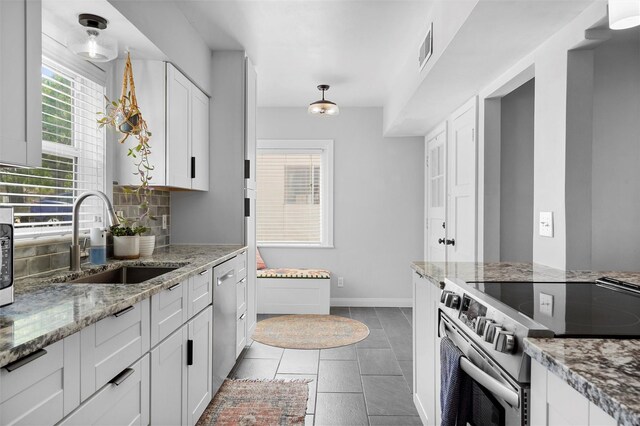 3177 Nickel Unit A, Los Alamos, NM 87544 - kitchen featuring appliances with stainless steel finishes, a sink, white cabinets, light stone counters, and dark tile patterned floors