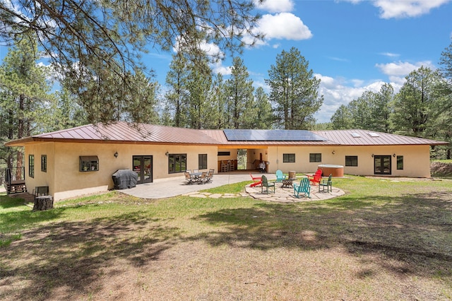 50 Jackson Hole Rd, Angel Fire, NM 87710 - rear view of house featuring french doors, stucco siding, a fire pit, solar panels, and a patio