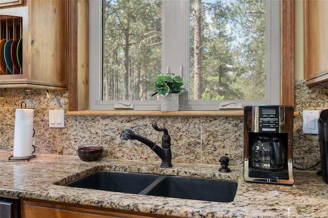 50 Jackson Hole Rd, Angel Fire, NM 87710 - kitchen view of a sink, backsplash, light stone countertops, and brown cabinetry