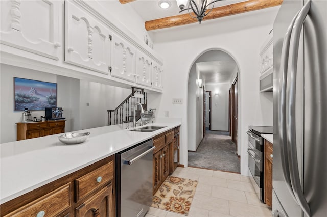 1905 Camino Redondo, Los Alamos, NM 87544 - kitchen with stainless steel appliances, a sink, arched walkways, beamed ceiling, and light countertops