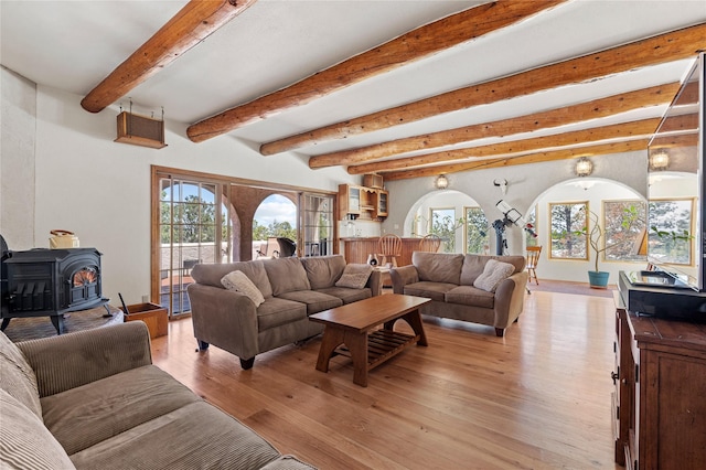 1905 Camino Redondo, Los Alamos, NM 87544 - living area with a wood stove, arched walkways, beam ceiling, and light wood-type flooring