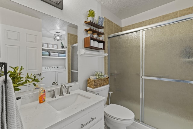 1086 Village Way, Santa Fe, NM 87507 - bathroom featuring washing machine and dryer, a textured ceiling, toilet, vanity, and a shower with shower door