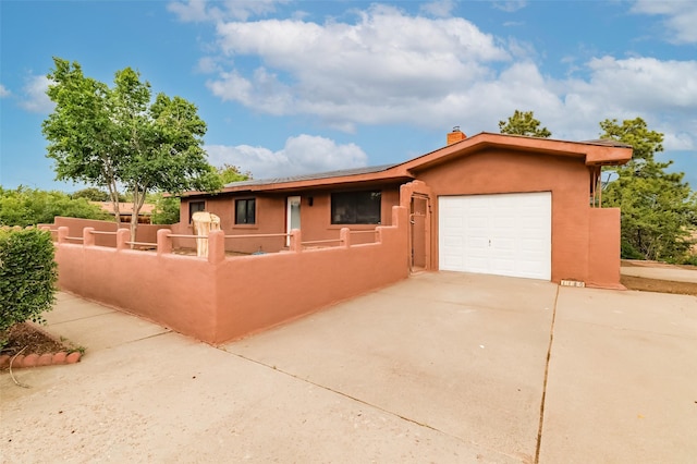 1180 Sioux, Los Alamos, NM 87544 - view of front facade featuring concrete driveway, an attached garage, stucco siding, and a chimney
