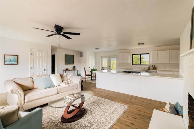 1180 Sioux, Los Alamos, NM 87544 - living room featuring light wood-type flooring, a fireplace, a ceiling fan, and french doors