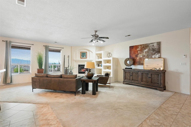1810 Eucalyptus Rd NE, Rio Rancho, NM 87144 - tiled living room with carpet floors, ceiling fan, a textured ceiling, built in features, and a glass covered fireplace