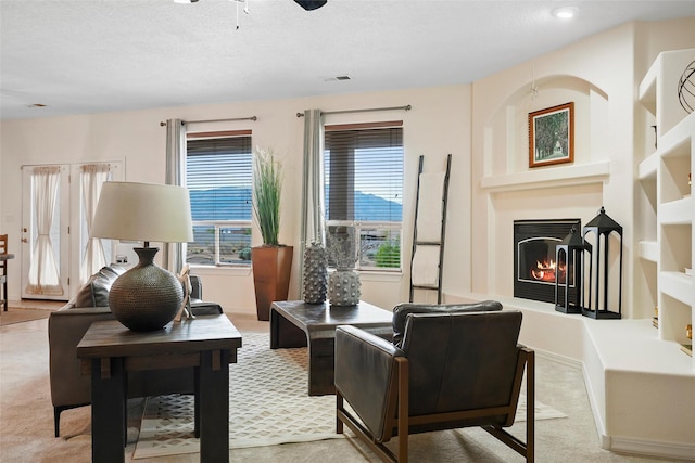 1810 Eucalyptus Rd NE, Rio Rancho, NM 87144 - carpeted living area with built in features, a warm lit fireplace, a ceiling fan, a textured ceiling, and recessed lighting