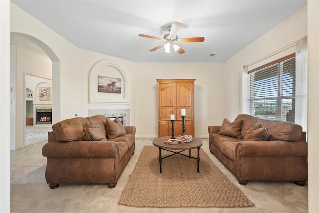 1810 Eucalyptus Rd NE, Rio Rancho, NM 87144 - living room featuring a ceiling fan, light carpet, arched walkways, and a lit fireplace