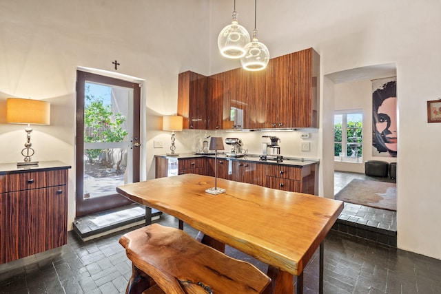 519 E Palace Ave, Santa Fe, NM 87501 - kitchen featuring modern cabinets, dark countertops, a towering ceiling, pendant lighting, and brown cabinetry