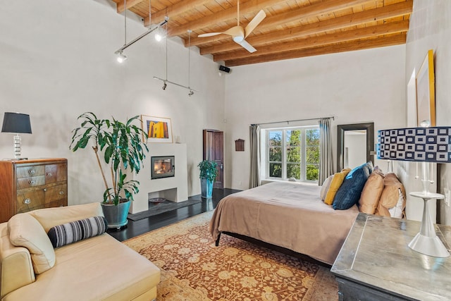 519 E Palace Ave, Santa Fe, NM 87501 - bedroom with wooden ceiling with exposed beams, a glass covered fireplace, wood finished floors, a ceiling fan, and a towering ceiling
