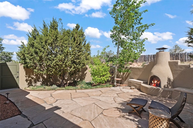 557 Valle Chamiso Ln, Santa Fe, NM 87505 - fenced backyard with a lit fireplace and a patio