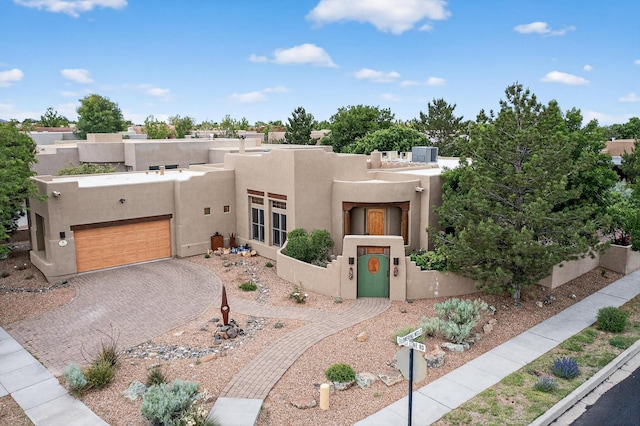 138 E Chili Line, Santa Fe, NM 87508 - southwest-style home with stucco siding, decorative driveway, cooling unit, and a garage