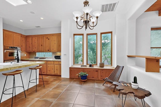 138 E Chili Line, Santa Fe, NM 87508 - kitchen with light countertops, recessed lighting, light tile patterned flooring, a chandelier, and a breakfast bar area