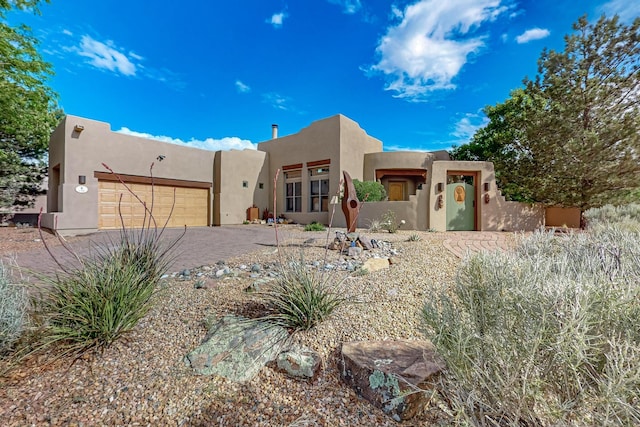 138 E Chili Line, Santa Fe, NM 87508 - adobe home featuring stucco siding, a garage, and decorative driveway